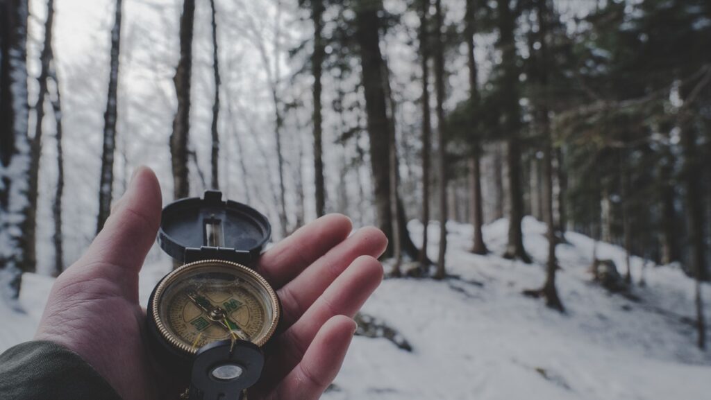 man holding compass in the snow