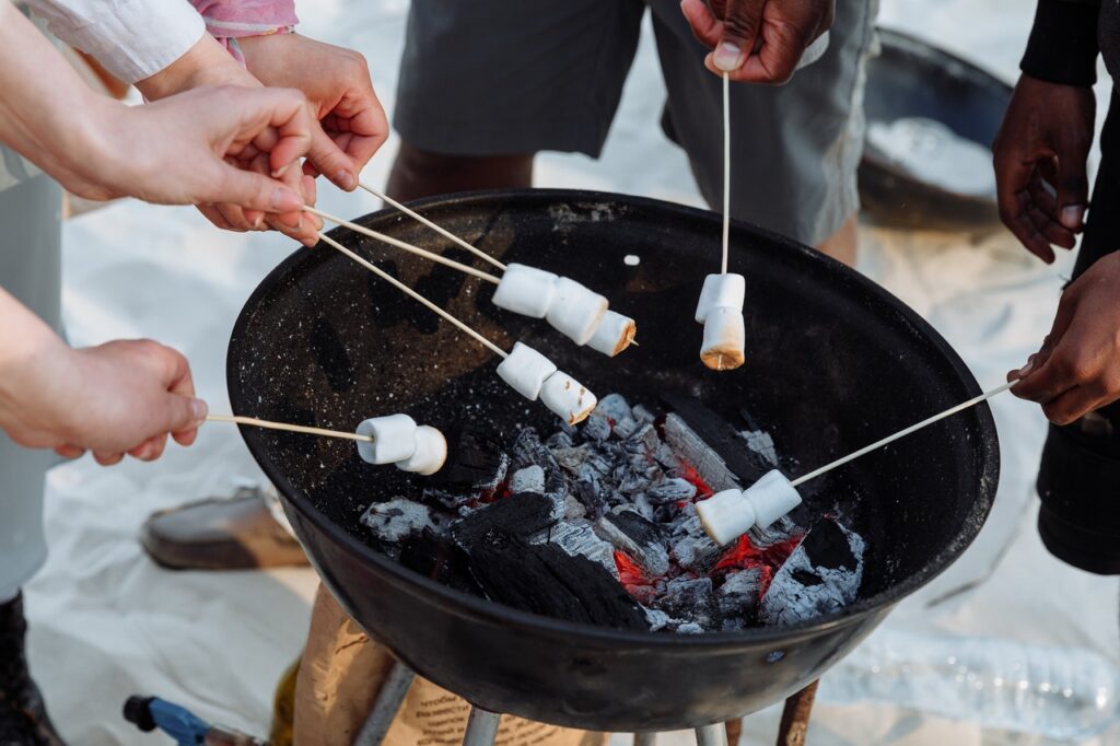 people roasting marshmallows over a hibachi grill