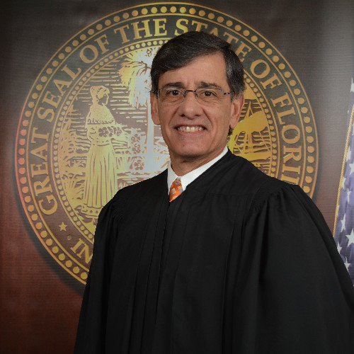 Judge Peter R. Lopez posing in front of Florida State seal